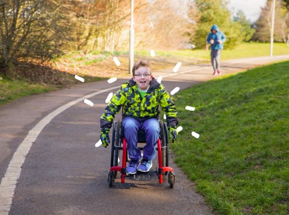A young wheelchair user pushed himself down a pathway