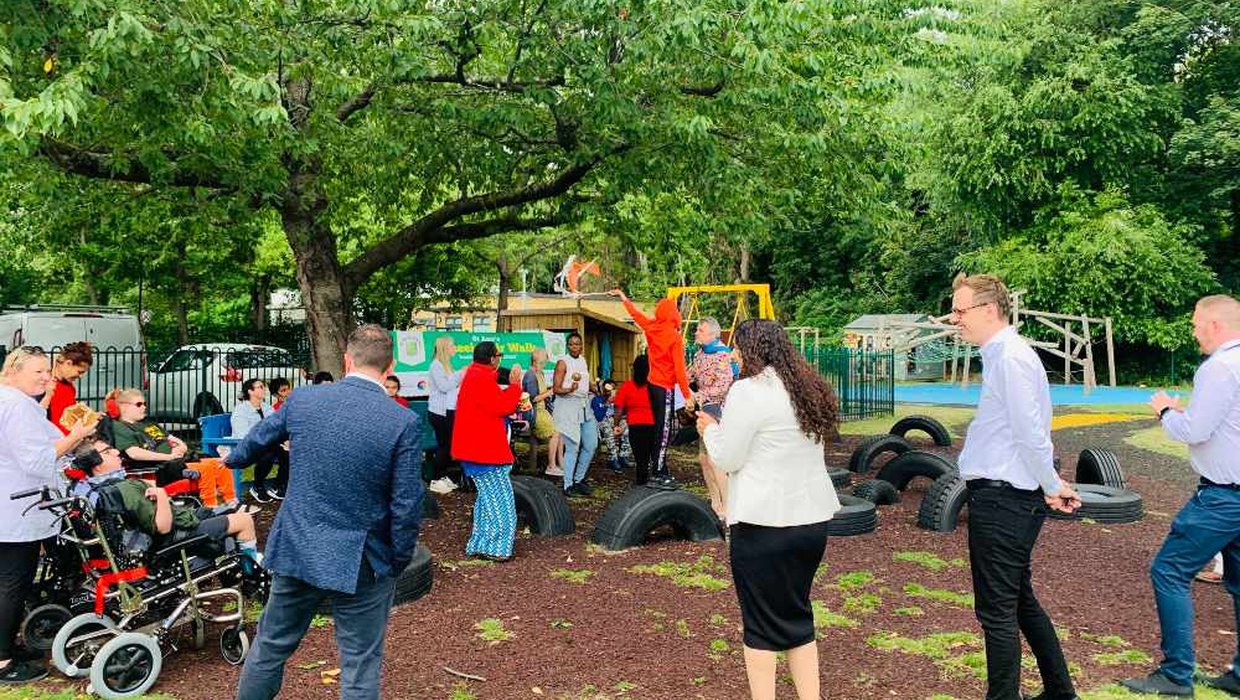 A group of young wheelchair users with adults in a grassy area