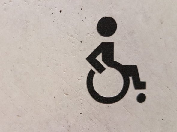A black wheelchair icon on a concrete style background