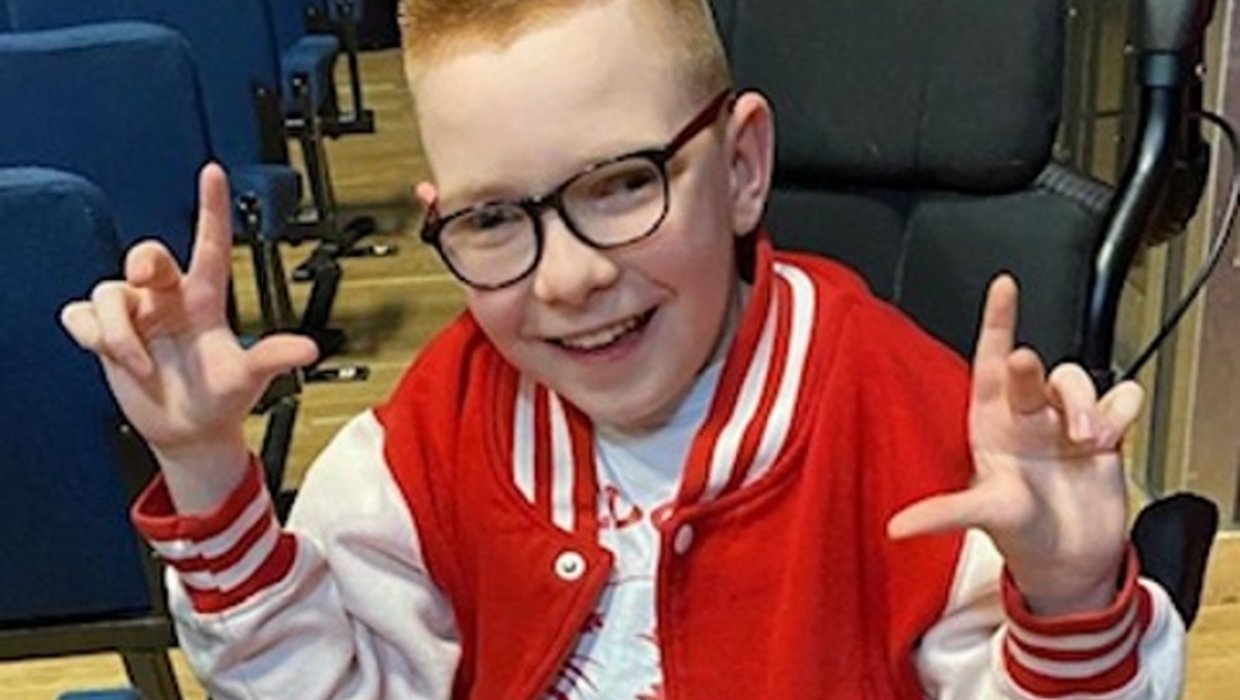 Logan appeared onstage in High School Musical and knew all the words Logan in a red baseball jacket, posing for the camera